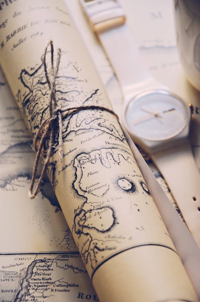 Close-up of a rolled vintage map tied with string, accompanied by a wristwatch.